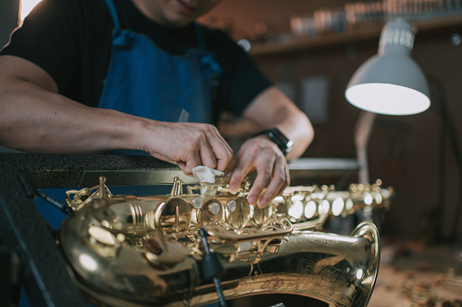 asian chinese male expertise repairing restoring alto saxophone at his work place
