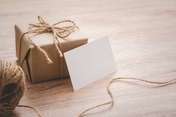 istock Gift box wrapped in craft paper with a white mockup gift card space 1273859737