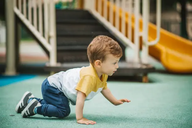 Baby boy crawling in public park.