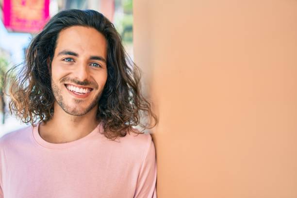 istock Young hispanic man smiling happy looking to the camera leaning on the wall. 1273861185