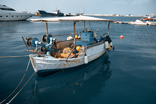 A scenic view of an old rusty blue and white fishing boat anchored in a port.