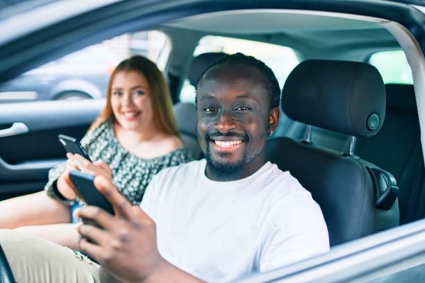 istock Young interracial couple smiling happy using smartphone at the car. 1273862309