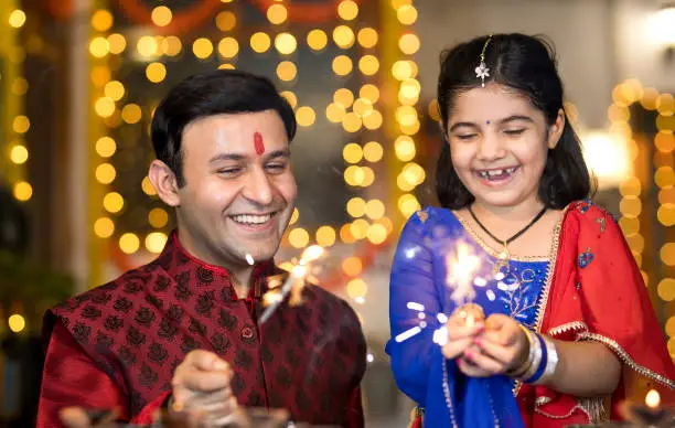 Photo of Father and daughter playing with crackers during Diwali festival
