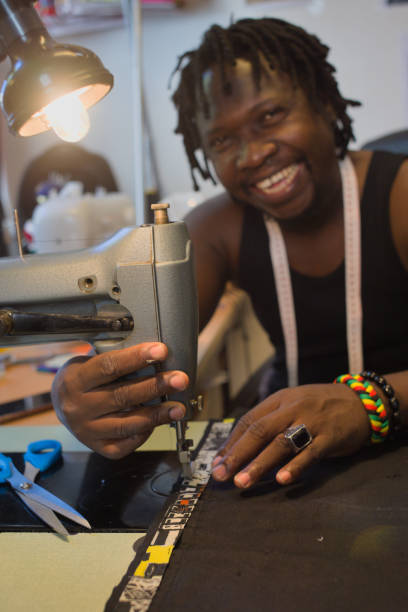 istock a smiling fashion designer sewing with his sewing machine 1273862698
