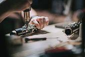 Asian chinese man checking and repairing Soprano saxophone music wind instrument in his workshop