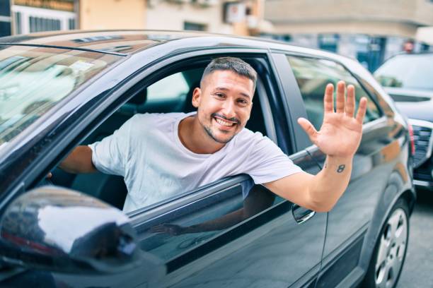 istock Young hispanic man smiling happy sitting on the car. 1273863649