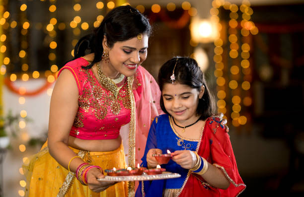 Loving mother and daughter decorating with Diya oil lamps on the occasion of Diwali festival celebration