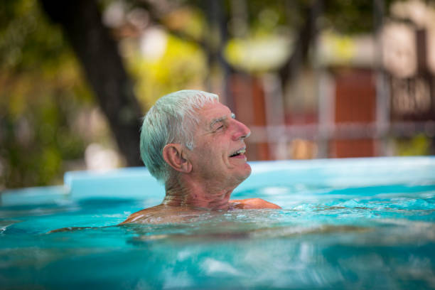 istock Smiling Senior Man Relaxing in Swimming Pool in Backyard 1273863817