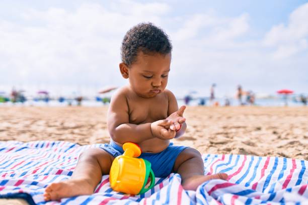 enfant en bas âge afro-américain d’adorable jouant avec des jouets s’asseyant sur le sable à la plage. - large and small photos et images de collection