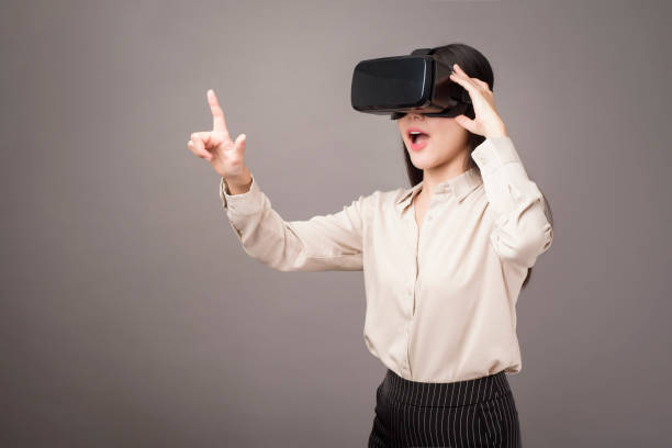 istock beautiful woman is using virtual reality on gray background 1273865770