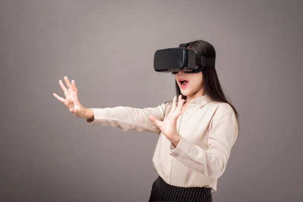 istock beautiful woman is using virtual reality on gray background 1273865873