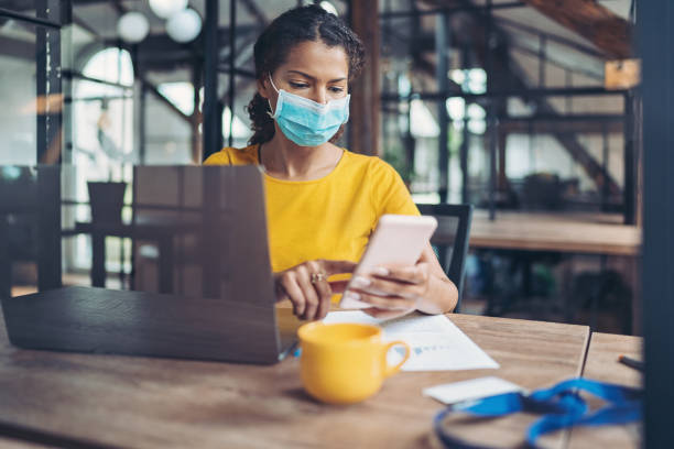 istock Young woman with a face mask using cell phone 1273866249