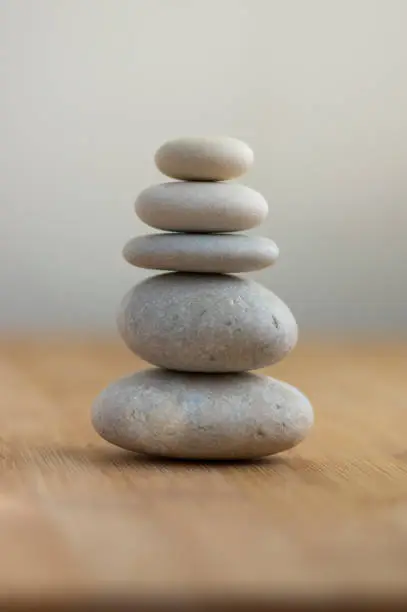 Photo of One simplicity stones cairn isolated on white background, group of light white pebbles in tower