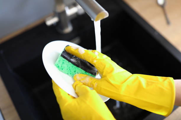 istock Gloved hands wash dishes under pressure water 1273867970