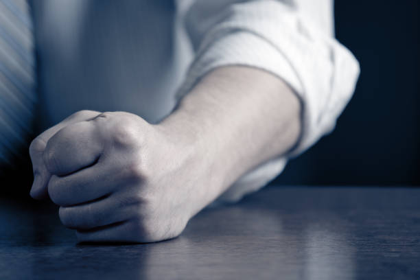 Close-up photo of a businessman (politician) hitting the desk with his clenched fist. Shallow depth of field - focus on the fist. Space for copy. Can illustrate the concept of stress, disagreement, anger, etc.