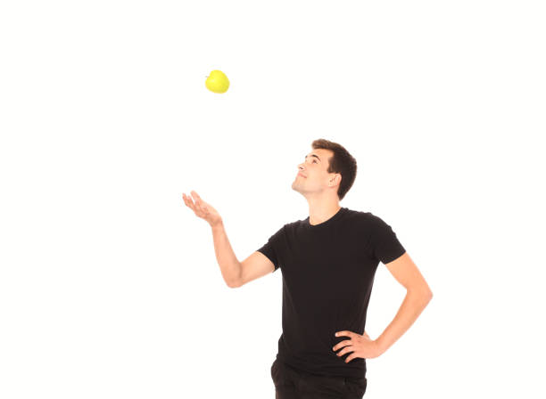 istock Young handsome man is throwing an apple. Copy space and selective focus 1273869253