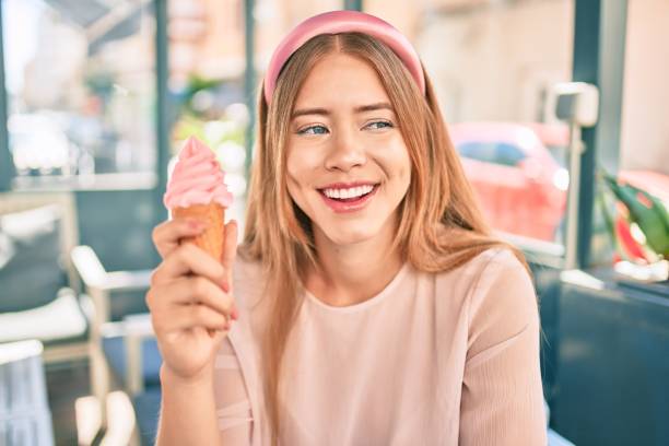 kuvapankkikuvat ja rojaltivapaat kuvat aiheesta nuori valkoihoinen tyttö hymyilee onnellisena syömällä jäätelöä istuen kahvilan terassilla. - diadem