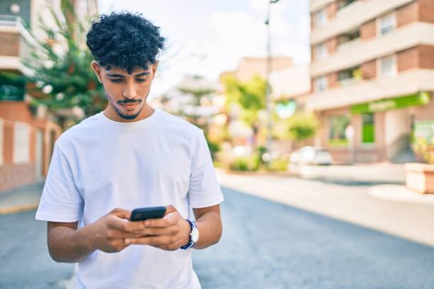 istock Young arab man with serious expression using smartphone walking at city. 1273871781