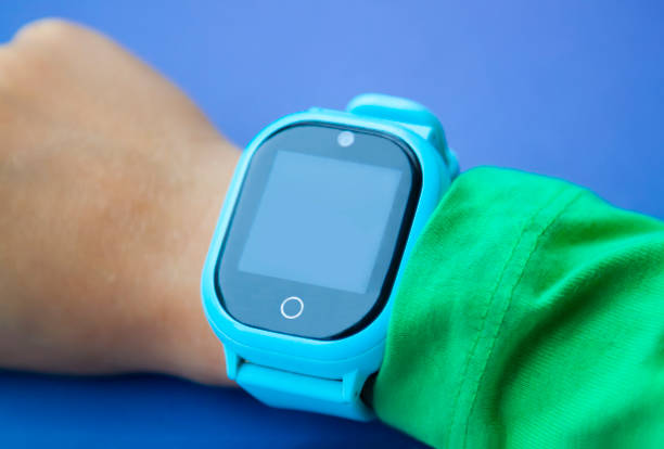 istock Blue smart digital watch on boy hand with green sleeve. Modern children technologies. GPS tracker for kids, child tracking and parental control concept. 1273872075