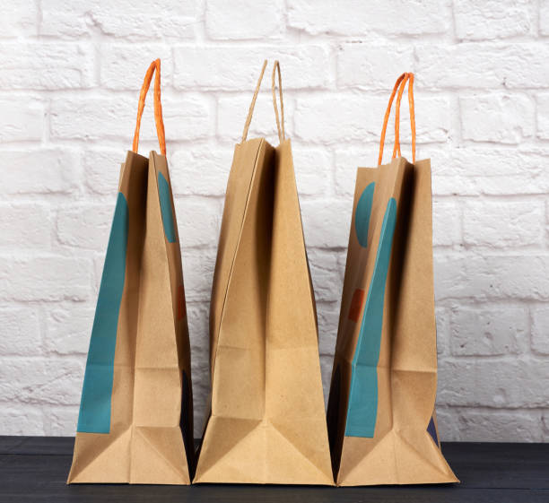 istock brown paper bag with handles on white brick wall background 1273873201