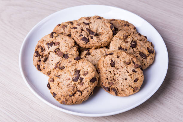 z bliska czekoladowych ciasteczek na białym talerzu na drewnianym stole - chocolate chip cookie bakery chocolate homemade zdjęcia i obrazy z banku zdjęć