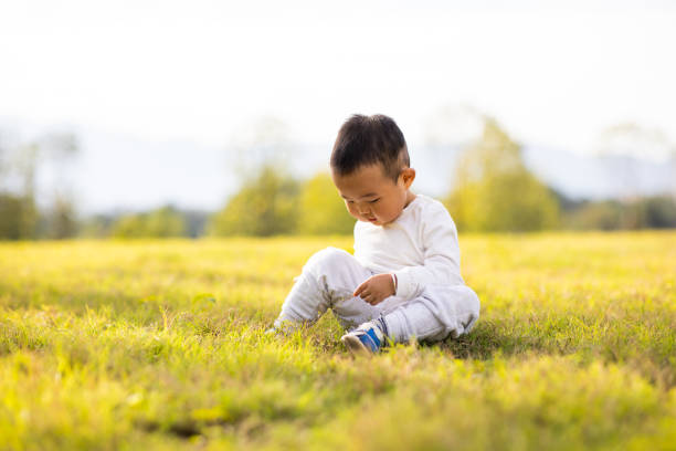 Asian baby boy sitting on lawn playing self