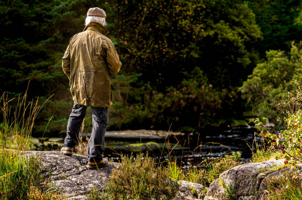istock Active senior man standing on a granite rock looking at a Scottish river in rural south west Scotland. 1273875520