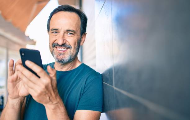 istock Middle age man with beard smiling happy outdoors using smartphone 1273876179