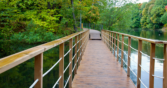 Suspension bridge and walking wooden path over the lake on an autumn evening