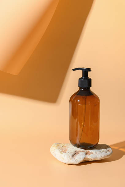 istock Glass bottle for soap, SPA, cosmetic care. Monochrome vertical creative composition on beige. 1273877027