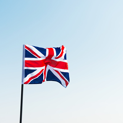 Flag of the United Kingdom waving against blue sky.