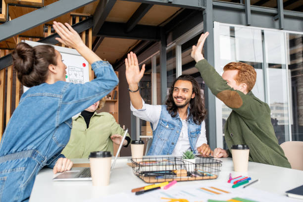istock Four young joyful and successful colleagues giving each other high five 1273878127