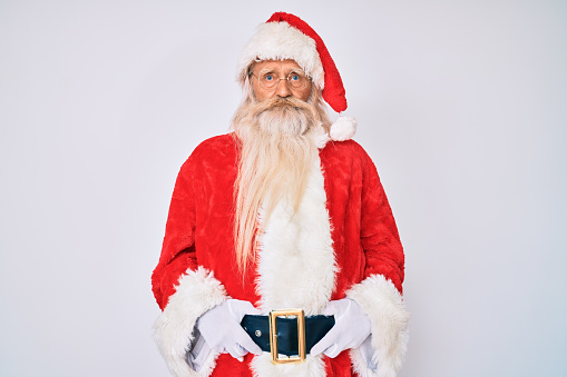 Old senior man with grey hair and long beard wearing santa claus costume with suspenders depressed and worry for distress, crying angry and afraid. sad expression.