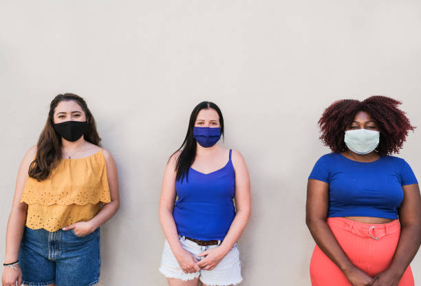istock Multiracial girlfriends standing in a line with social distance while wearing protective face mask for coronavirus 1273878244