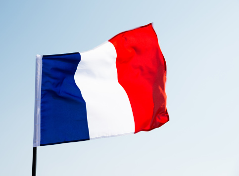 Flag of France waving against blue clear sky.