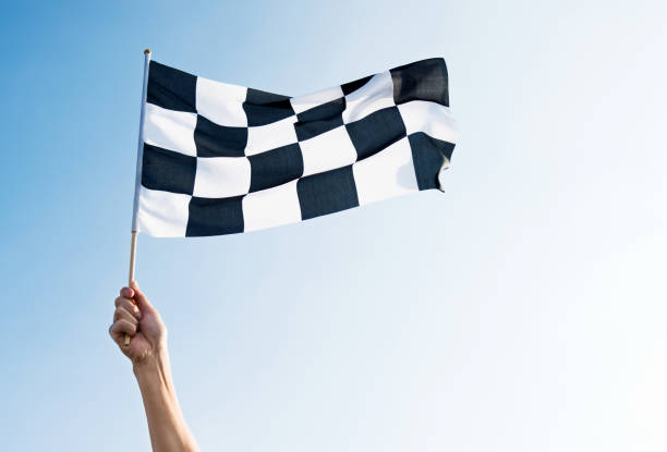 istock Man hand holding checkered flag in the wind 1273878665