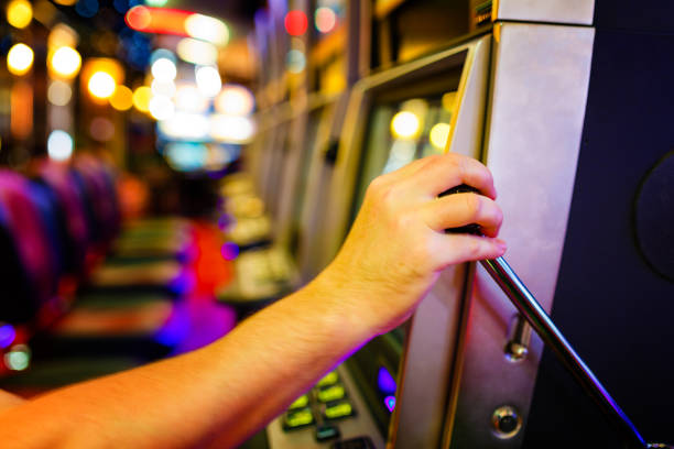 istock Man pulling down lever of slot machine in casino 1273879521