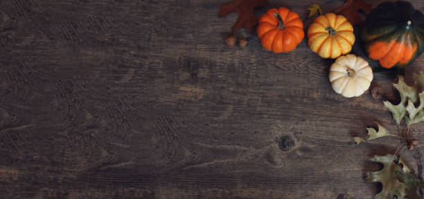istock Fall Thanksgiving and Halloween pumpkins, leaves, acorn squash over rustic dark wood table background shot from directly above, horizontal 1273879525