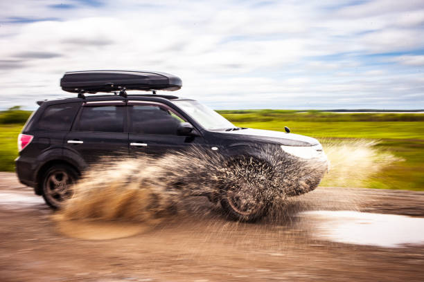 black subaru forester dirigindo em uma estrada de terra com poças. a água espirra debaixo das rodas. desfoque de movimento - recreate - fotografias e filmes do acervo