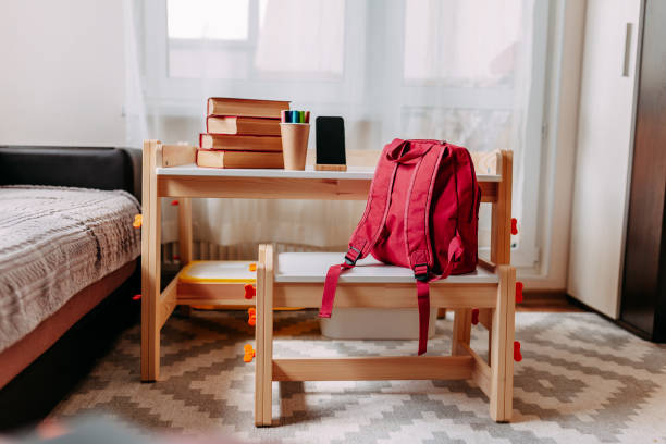 material escolar na mesa da escola. mochila vermelha, fones de ouvido brancos, notebook, grandes livros vermelhos, canetas no pote estava na mesa branca da escola. - school supplies pencil colors apartment - fotografias e filmes do acervo