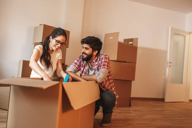 istock Young couple unpacking cardboard boxes at new home. 1273880874