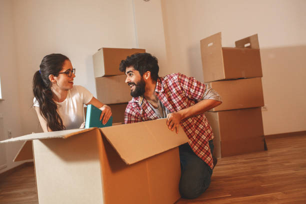 istock Young couple unpacking cardboard boxes at new home. 1273881128