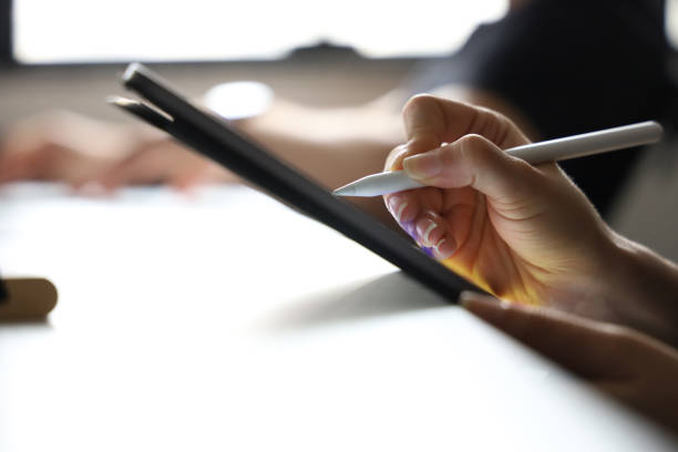 istock Close up of female hand using digital pen writing on digital tablet screen 1273883087