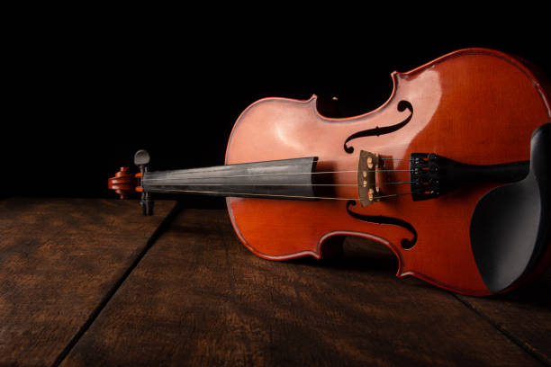 istock Old and beautiful violin on a rustic wooden surface and black background low key portrait, selective focus. 1273883099