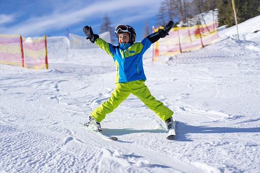 6 years old very happy boy child skiing in snowlpow on sunny winter vacation day on ski slope