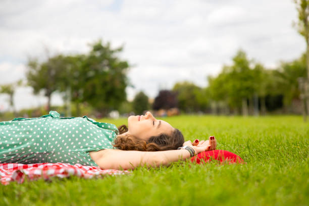 istock Beautiful woman resting on the grass in a park 1273888604
