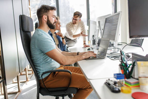 istock Young male programmer sitting at the desk in his office and working . 1273890272