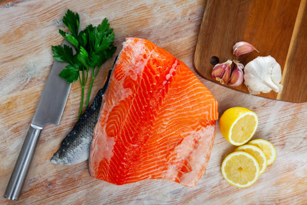 istock Appetizing raw salmon fillet with lemon and greens 1273894443