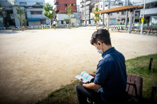 Men reading a book outdoors.