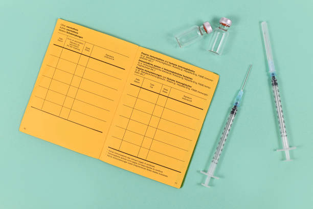 Concept for vaccination with syringes, vials and empty yellow international certificate of vaccination